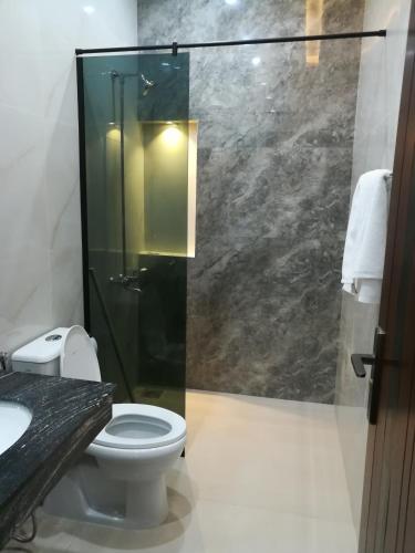 a bathroom with a toilet and a glass shower at Maskan in Islamabad