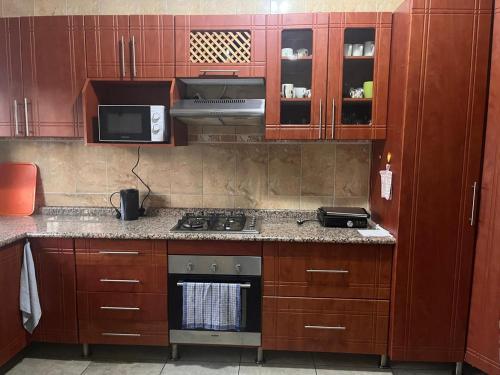 a kitchen with wooden cabinets and a stove top oven at Acomodação Nunes in Matola