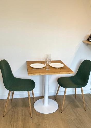 une table avec deux chaises vertes et une table avec deux assiettes dans l'établissement Studio avec jardin proche lac, à Saint-Jorioz