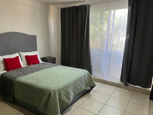 a bedroom with a bed with red pillows and a window at 3 VENATOR House Boutique in León
