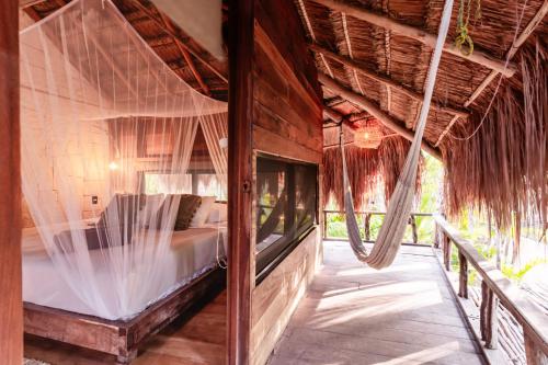 a bedroom with a bed in a room with a hammock at Vida Silvestre in Tulum