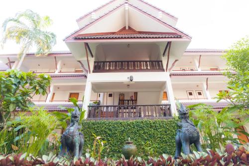 a house with two statues in front of it at Nak Nakara Hotel in Chiang Rai