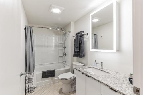 a white bathroom with a toilet and a sink at Sleek downtown Cleveland apartment in Cleveland
