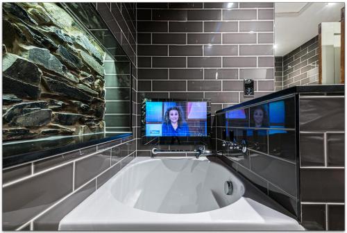 a bathroom with a tub with two monitors on the wall at Broadoaks Boutique Country House in Windermere