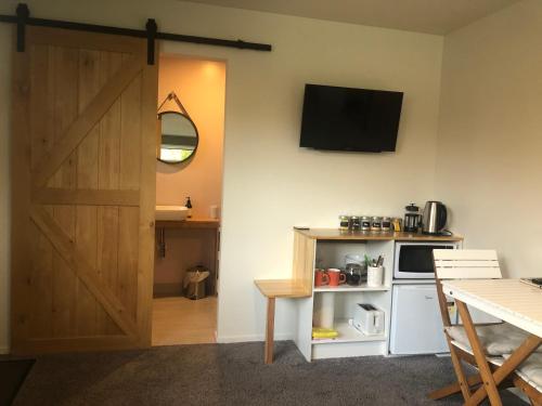 a room with a door and a kitchen with a microwave at East Rock - Cosy Guesthouse in Kelvin Heights in Queenstown