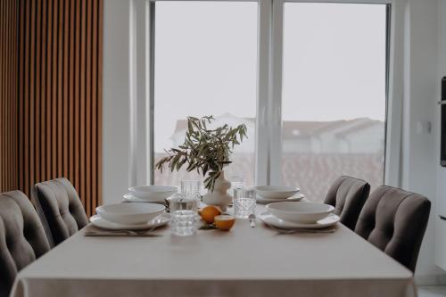 mesa de comedor con mantel y sillas blancas en Lili Rose Mandre Luxury Apartments en Mandre