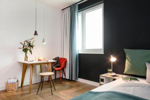 a bedroom with a bed and a desk and a window at SMARTments business Berlin Prenzlauer Berg in Berlin