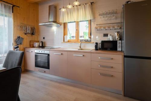 a kitchen with white cabinets and a sink and a microwave at Kuća za odmor Butković in Mrkopalj
