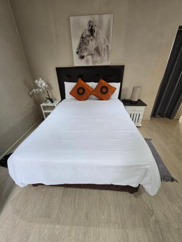 a bedroom with a large white bed with orange pillows at Three Flags in Pietermaritzburg