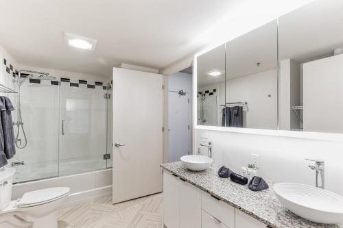 a white bathroom with two sinks and a shower at DT Delight Downtown Living Two-Bedroom Endless Access in Cleveland