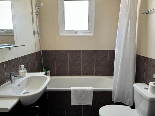 a bathroom with a sink and a tub and a toilet at Cosy apartment at Mythical Sands resort in Paralimni