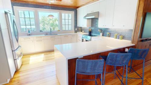 a kitchen with white cabinets and blue bar stools at 3 10th Place by Tybee Vacation Rentals in Tybee Island