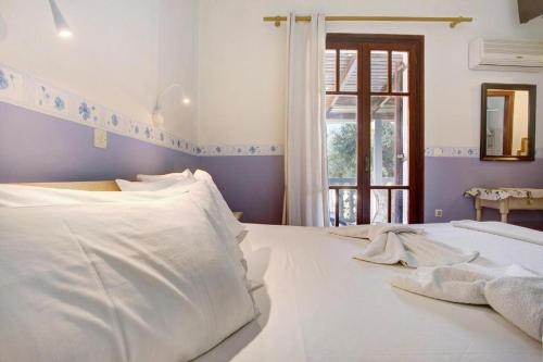 a bedroom with a white bed and a window at Areti Orfeas Studios in Vasilikos