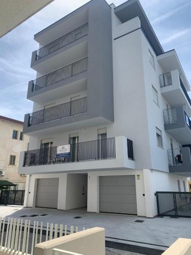 a tall white building with two garage at Matilde Apartments Caorle in Caorle