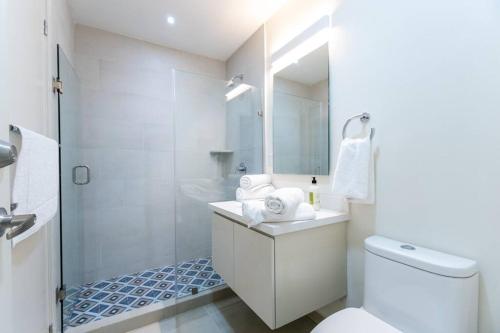 une salle de bain blanche avec toilettes et douche dans l'établissement Cristal bay 1504 lujosa habitación frente al mar, à Mazatlán