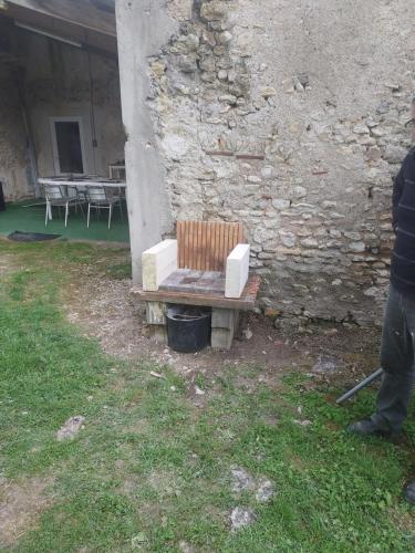 a wooden bench sitting next to a stone wall at Au chant des Grenouilles in Patay