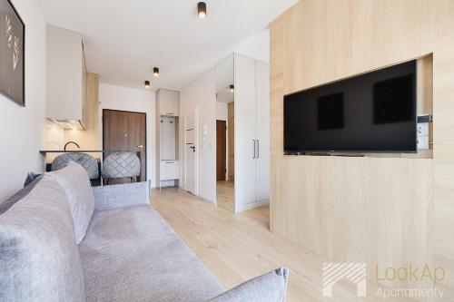 a living room with a couch and a television on a wall at Boho Prestige by LookAp in Łódź