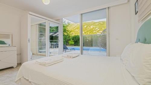 Dormitorio blanco con cama y ventana grande en Villa White Stone, en Kalkan