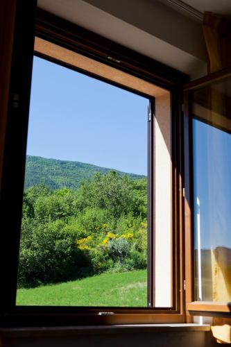 a window with a view of a green field at Relais Parco Del Subasio in Piano Delle Pieve