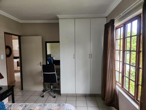a bedroom with white cabinets and a chair next to a window at Three Flags in Pietermaritzburg
