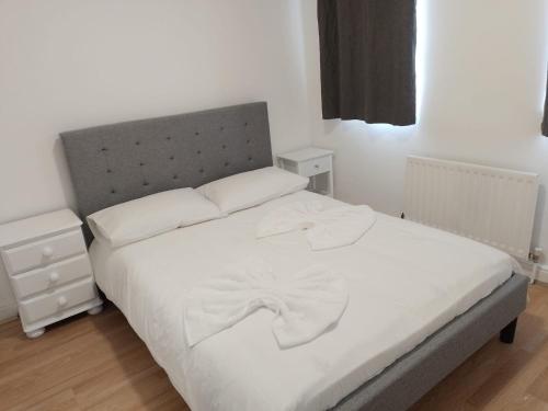 a bedroom with a white bed with a gray headboard at City Guest House se1 in London