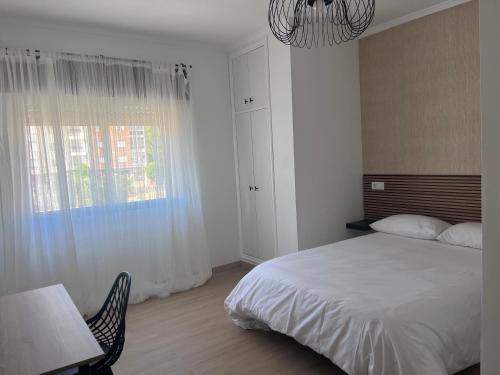 a bedroom with a bed and a table and a window at Hostal DIMAR in Quiroga