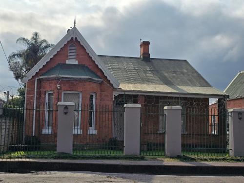 an old red brick house with a fence at Three Flags in Pietermaritzburg