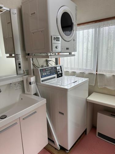 a small kitchen with a sink and a microwave at Guest house En in Fujiyoshida