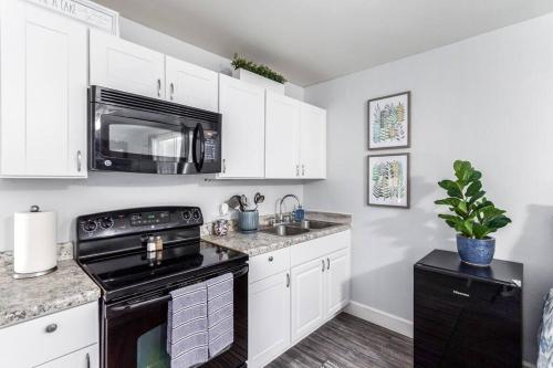 a kitchen with white cabinets and a black stove top oven at The Cutest Little Studio, Free Parking, Tempe in Tempe