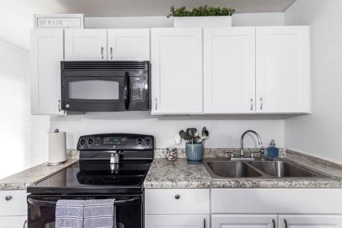 a kitchen with white cabinets and a black microwave at The Cutest Little Studio, Free Parking, Tempe in Tempe