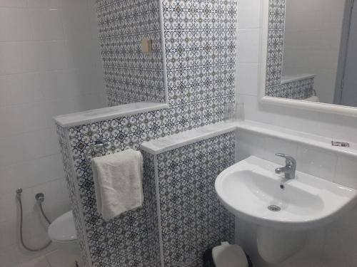 La salle de bains blanche est pourvue d'un lavabo et d'un miroir. dans l'établissement Hotel Le Khalife, à Hammamet