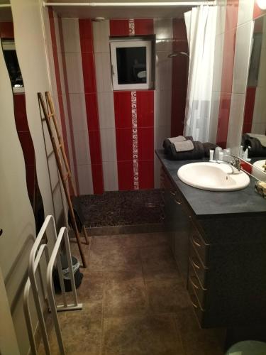 La salle de bains est pourvue d'un lavabo et d'un mur rouge et blanc. dans l'établissement Côte Dors, à Corpeau