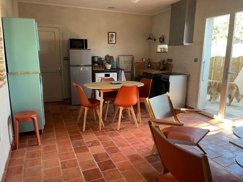 une cuisine avec une table, des chaises et un réfrigérateur dans l'établissement La maison des Dames Marie, à Coursan