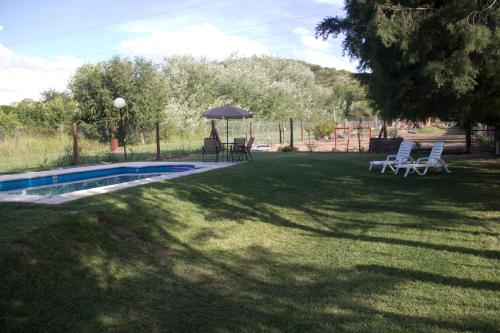 a yard with a pool and chairs and an umbrella at Koslayna in Potrero de los Funes