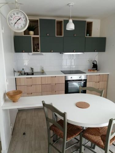 une cuisine avec une table et une horloge au mur dans l'établissement Rez de jardin, St Brevin les Pins, plage à pieds, à Saint-Brévin-les-Pins