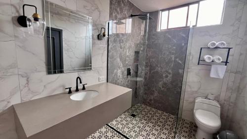 a bathroom with a sink and a toilet and a mirror at Hotel Varadero Internacional in Guayaquil