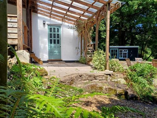 a white house with a blue door in a garden at Offa's Hideaway - Wye Valley in Newland
