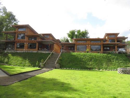 une grande maison en bois avec une pelouse verte en face de celle-ci dans l'établissement Cabañas El Roble Lican Ray, à Licán Ray