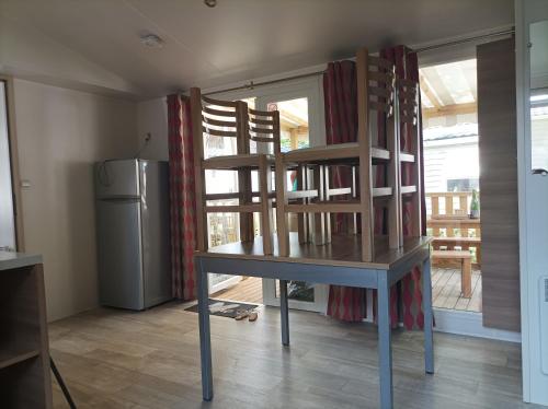 La cuisine est équipée d'une table, de deux chaises et d'un réfrigérateur. dans l'établissement Mobil-Home 6-8 personnes, à Saint-Jean-de-Monts