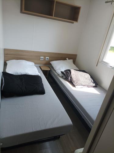 deux lits jumeaux dans une chambre avec fenêtre dans l'établissement Mobil-Home 6-8 personnes, à Saint-Jean-de-Monts