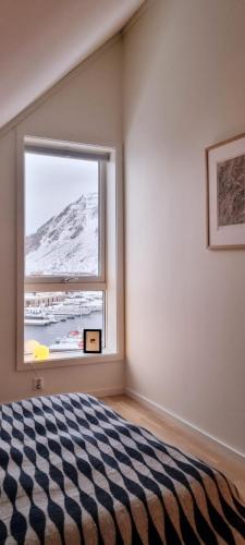 a bedroom with a bed and a large window at Two-story apartment with private deck in Ballstad