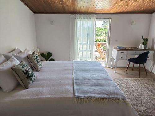 a bedroom with a large bed with a desk and a window at Casinha do Chico in Charneca
