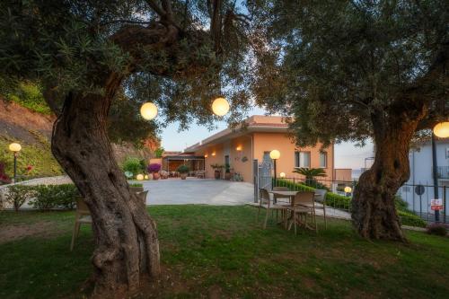 a house with a table and chairs under a tree at La Risacca Relais in Belvedere Marittimo