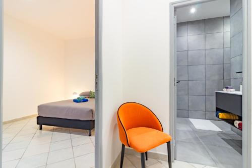 a bedroom with a bed and a orange chair at Spacieux appartement en plein Coeur de Béziers in Béziers