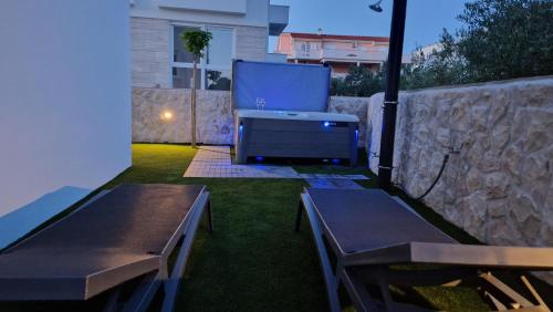 a backyard with two benches and a large screen tv at Luxury apartment Terracotta Sun with private Jacuzzi and Garden in Novalja