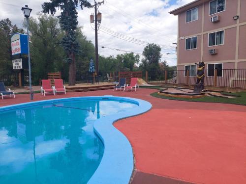 a swimming pool in front of a building with chairs at Manitou Inn in Manitou Springs