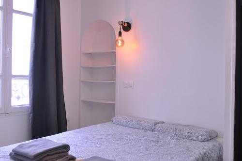 une chambre avec un lit et une lumière sur le mur dans l'établissement Appt Paris11 Charonne, à Paris
