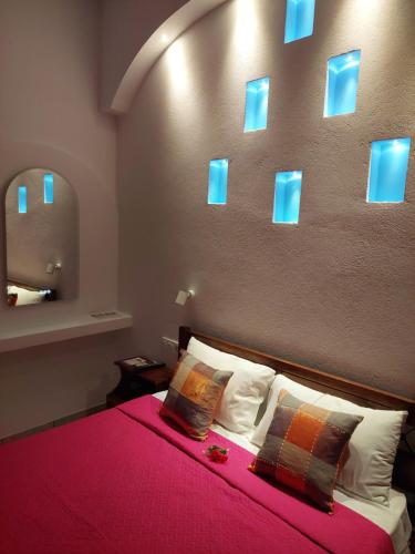 a bedroom with a bed with a red blanket and blue mirrors at Evelina Family Beach Pension a breath away from the Black Beach offer plenty of accommodation type to suit every traveler's needs-Economic Rooms-Thematic Rooms-Design Rooms-Kitchenette Rooms-Studios-Small Apartments in Perissa