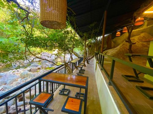 a balcony with tables and chairs and a river at Citrine Belihuloya in Belihul Oya