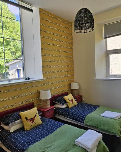 two beds in a room with two windows at Old School, Spean Bridge - fun, friendly, relaxed in Spean Bridge